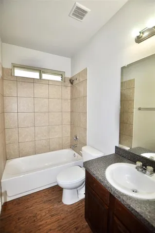 a bathroom with a granite countertop sink a toilet a mirror and bathtub