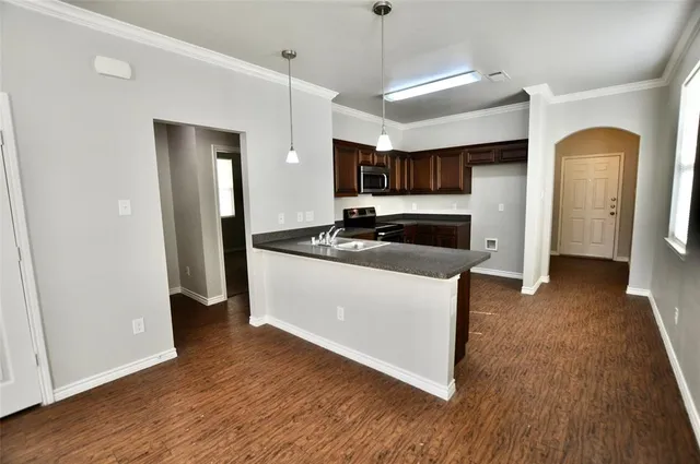 a kitchen with stainless steel appliances a refrigerator a sink a stove a microwave and wooden floors