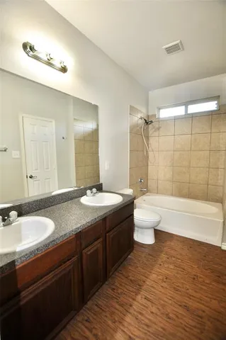 a bathroom with a granite countertop sink toilet mirror and bathtub