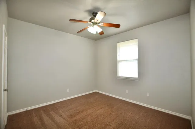 an empty room with window and chandelier fan