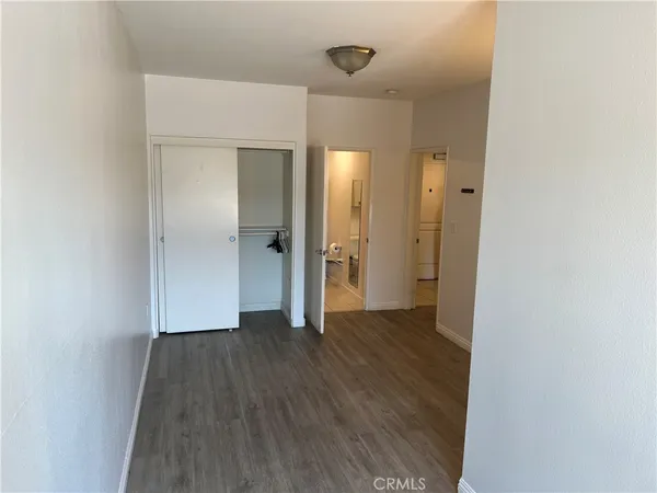 a view of an empty room with wooden floor and a mirror