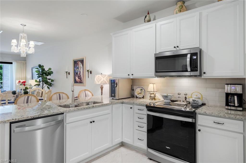 5948 Mayflower Way Ave Maria, FL 34142 - Photo 12 of 48 a kitchen with stainless steel appliances granite countertop a sink dishwasher a microwave oven and white cabinets with wooden floor