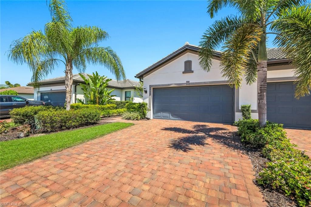5948 Mayflower Way Ave Maria, FL 34142 - Photo 2 of 48 a view of yellow house with a yard and palm trees