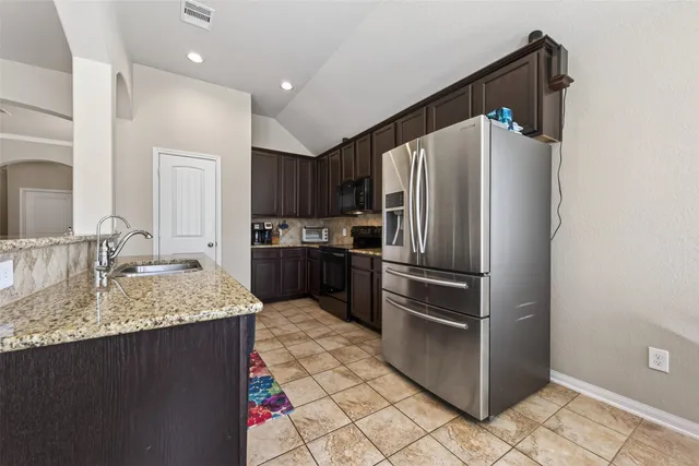 a kitchen with granite countertop a refrigerator stove and sink