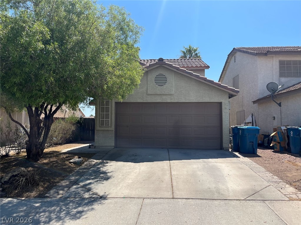 914 Scarlet Ridge Drive Las Vegas, NV 89128 - Photo 2 of 25 A well-maintained concrete driveway leads to a classic garage entrance, flanked by mature landscaping.
