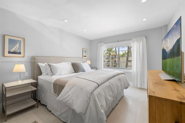 a spacious bedroom with a bed and a flat screen tv