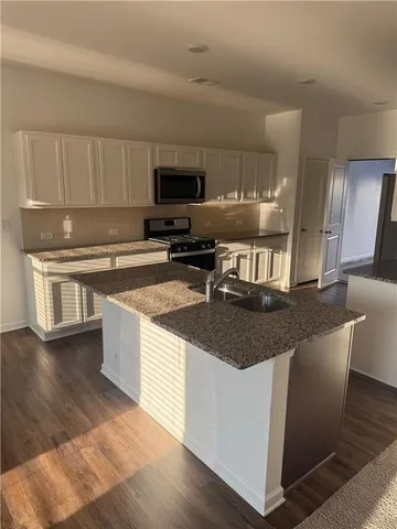 a kitchen with stainless steel appliances granite countertop a sink a stove top oven a counter space and cabinets