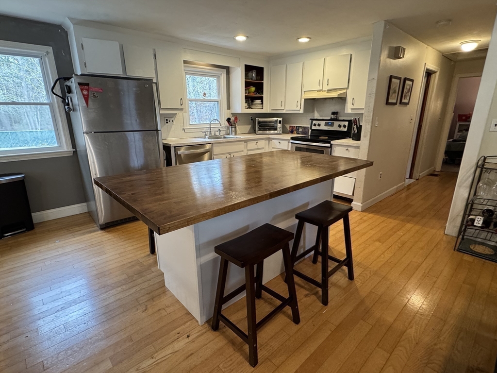77 Branch Road East Bridgewater, MA 02333 - Photo 7 of 16 a kitchen with stainless steel appliances granite countertop a refrigerator a stove a sink a dining table and chairs with wooden floor