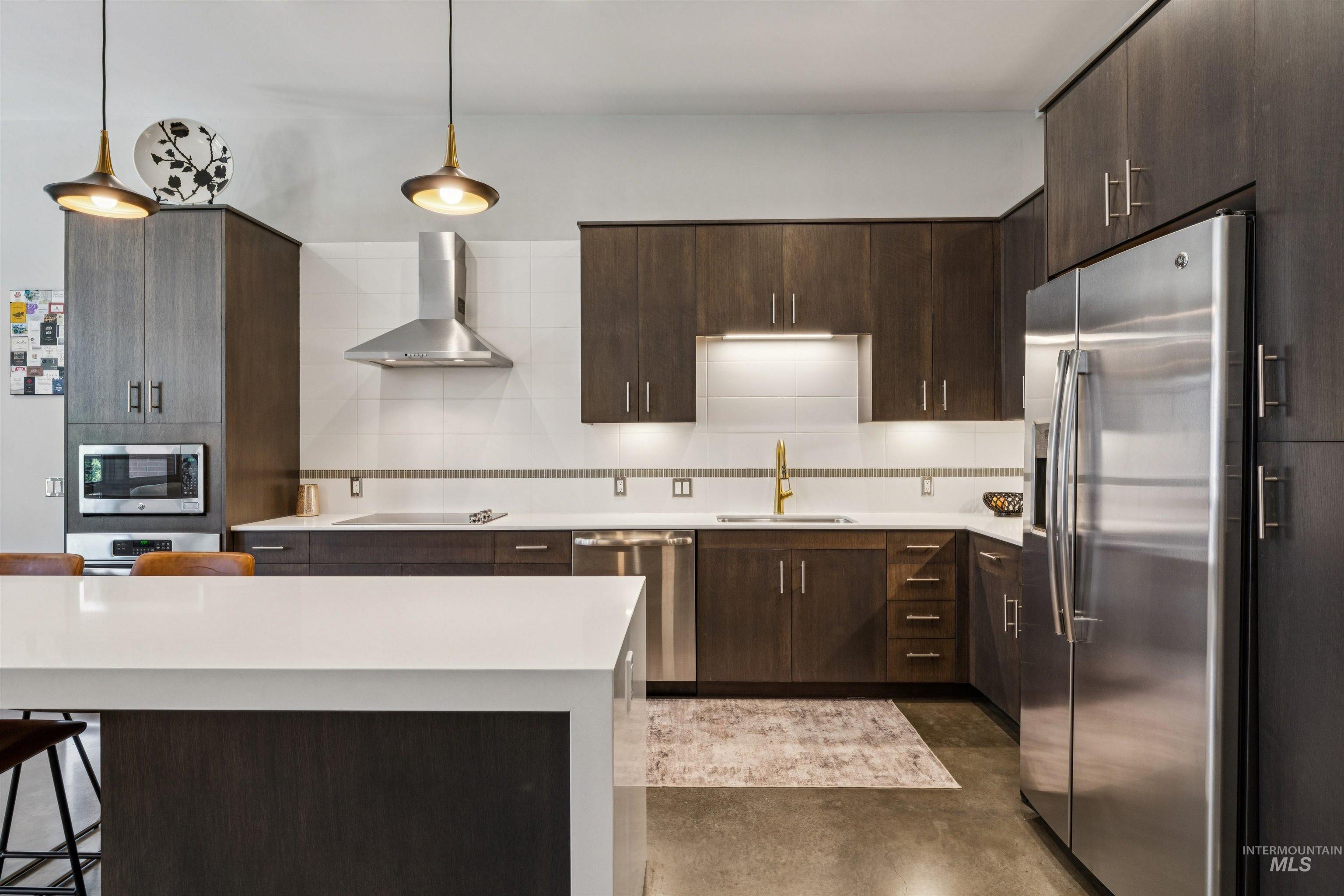 119 South 10th Street, Unit 307 Boise, ID 83702 - Photo 7 of 47 Modern kitchen with dark wood-finish cabinetry, stainless steel appliances, white quartz countertops, and a white tile backsplash
