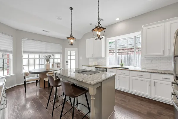 a open kitchen with stainless steel appliances granite countertop a stove a sink a dining table and chairs with wooden floor