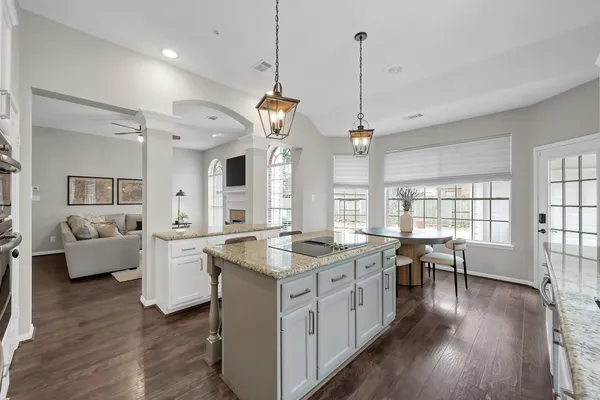 a open kitchen with stainless steel appliances granite countertop a stove a refrigerator a sink dishwasher with a dining table and chairs