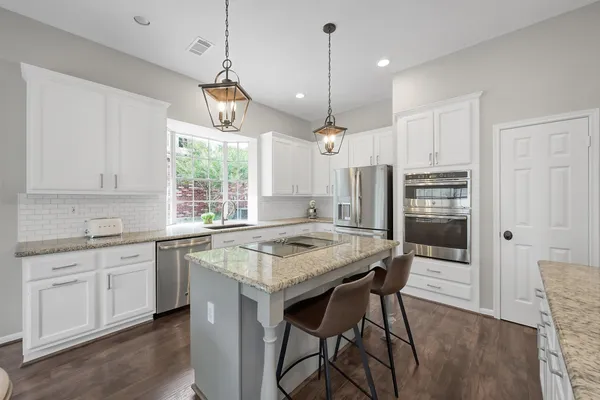 a kitchen with stainless steel appliances granite countertop a stove a sink refrigerator and a wooden cabinets