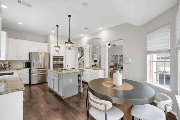 a kitchen with stainless steel appliances a dining table chairs and microwave