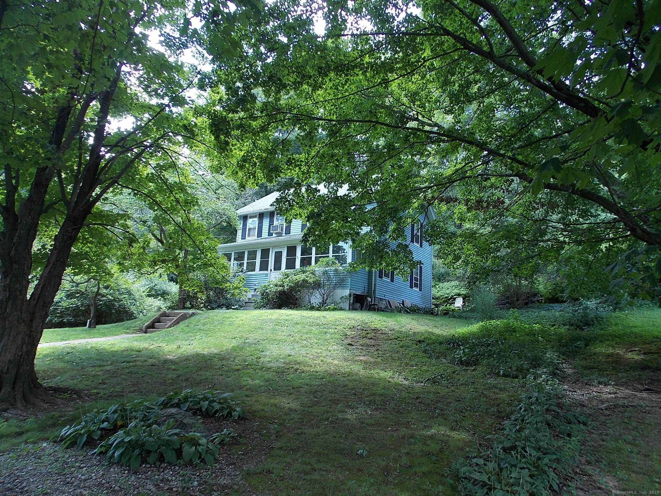 a view of a house with a big yard and large trees