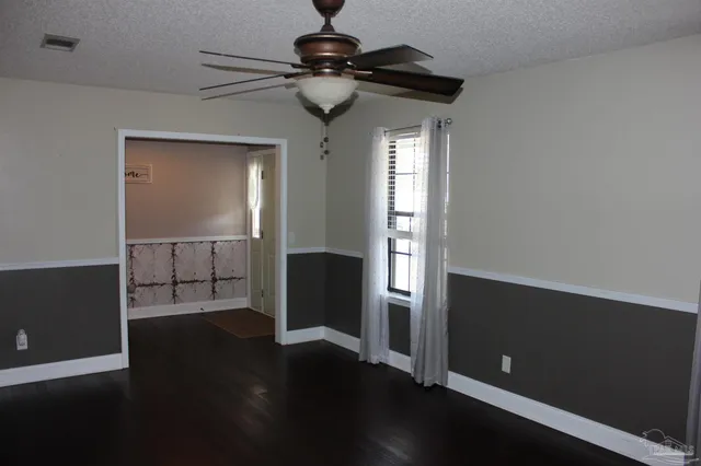 a view of an empty room with window and wooden floor
