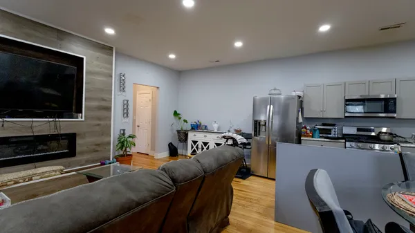 a living room with stainless steel appliances furniture a flat screen tv and view of kitchen