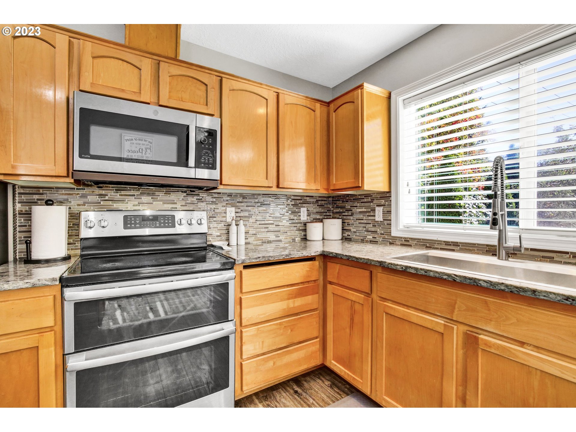 16128 Southeast Rural Court Portland, OR 97236 - Photo 12 of 37 a kitchen with granite countertop a stove microwave and sink
