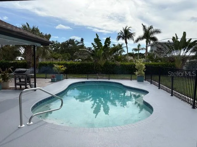 a view of swimming pool with outdoor seating and plants in the back