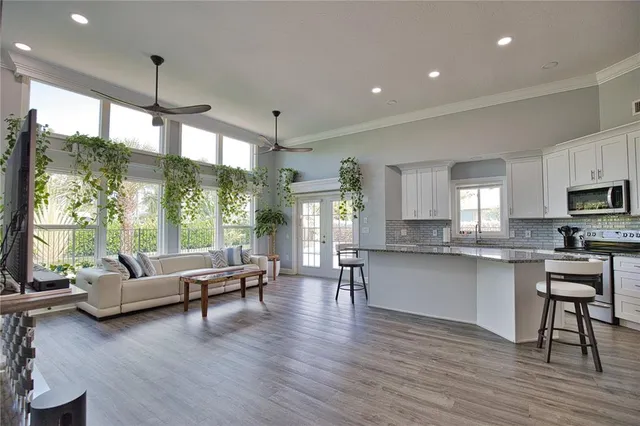 a living room with stainless steel appliances granite countertop furniture wooden floor and a view of kitchen