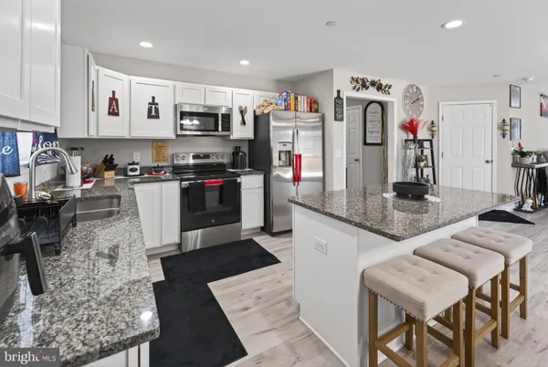 a kitchen with stainless steel appliances granite countertop a stove top oven a sink a dining table and chairs with wooden floor