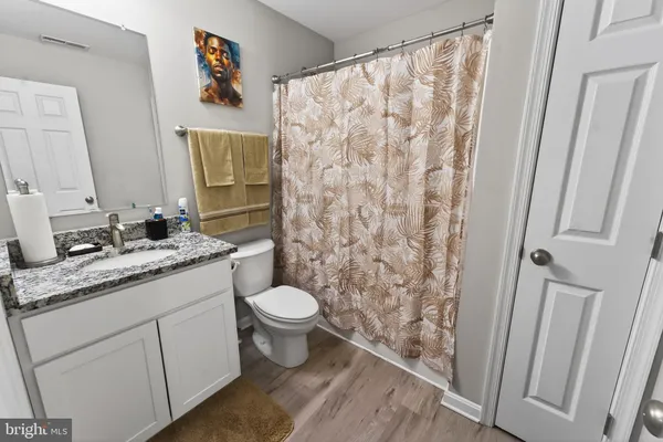 a bathroom with a granite countertop sink toilet and a mirror