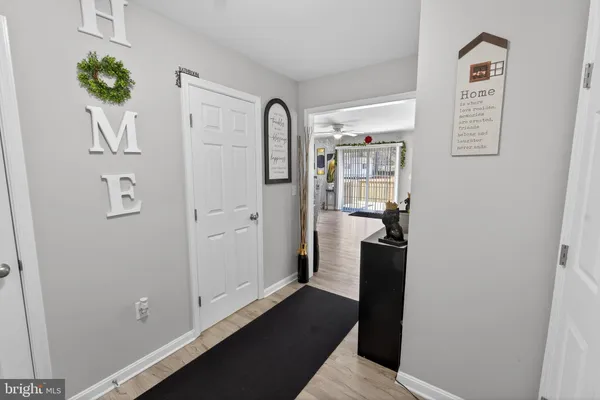 a view of a hallway with wooden floor and a bathroom