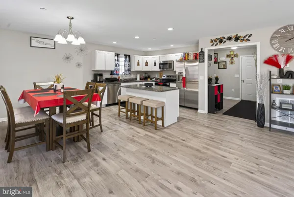 a kitchen with stainless steel appliances kitchen island granite countertop a table chairs and a refrigerator