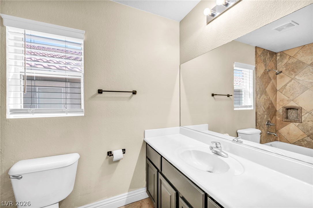 6405 North Raptor Court North Las Vegas, NV 89084 - Photo 28 of 66 A well-appointed bathroom features a single vanity, a standard toilet, and a tiled shower-bathtub combination.