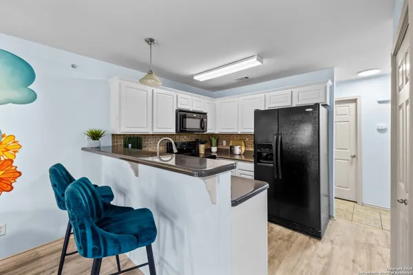 a kitchen with stainless steel appliances granite countertop a refrigerator a stove a sink dishwasher a dining table and chairs with wooden floor