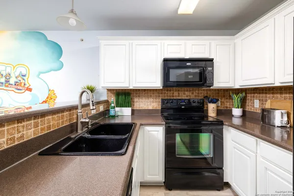 a kitchen with granite countertop a stove a sink and a microwave