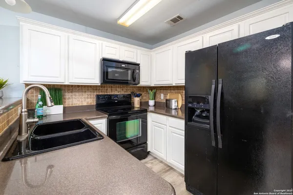 a kitchen with stainless steel appliances a refrigerator sink and white cabinets