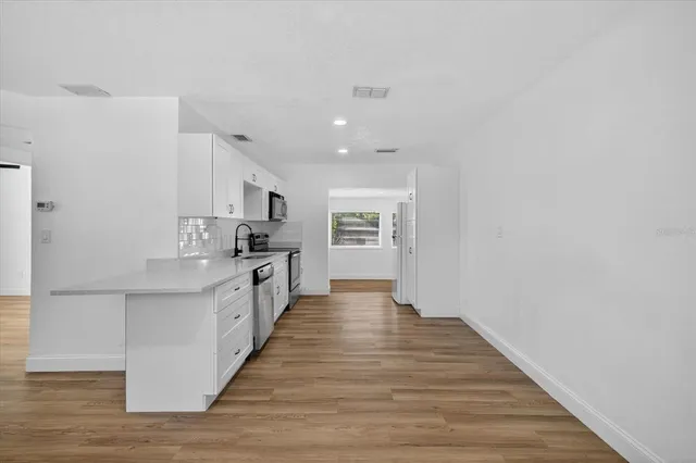 a large kitchen with cabinets wooden floor and stainless steel appliances