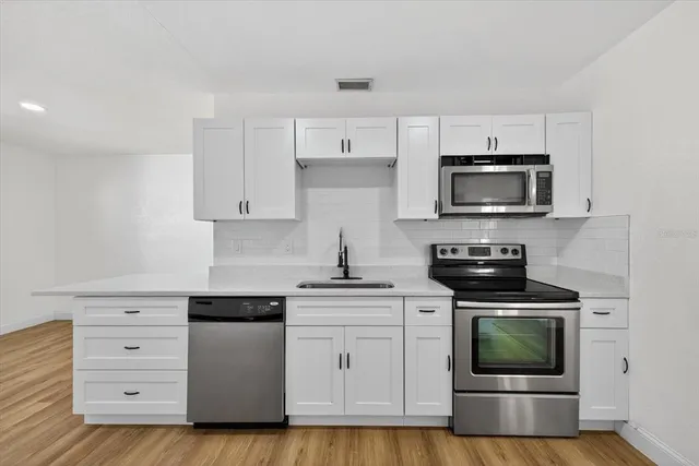 a kitchen with white cabinets and stainless steel appliances