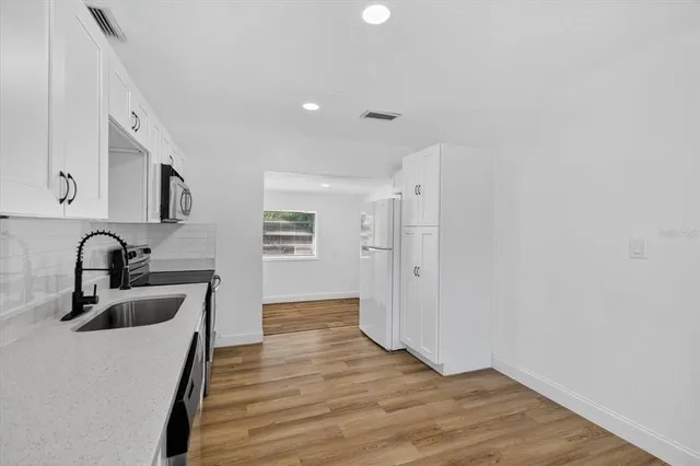 a kitchen with granite countertop a sink cabinets and wooden floor