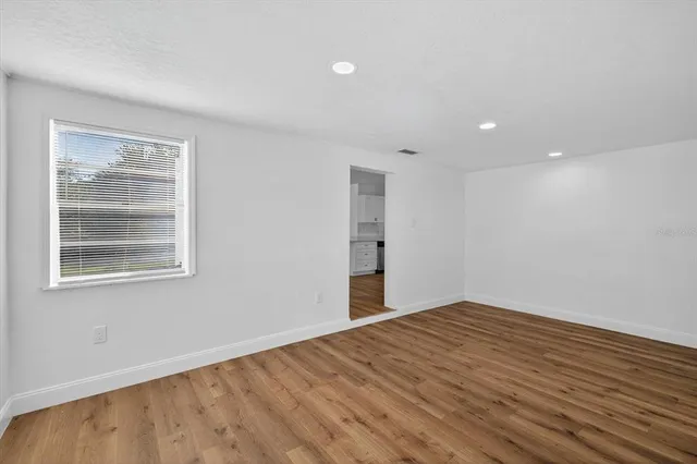 a view of empty room with wooden floor and fan