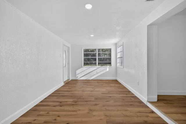 a view of empty room with wooden floor and fan
