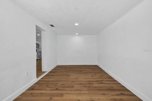 a view of an empty room with wooden floor and closet