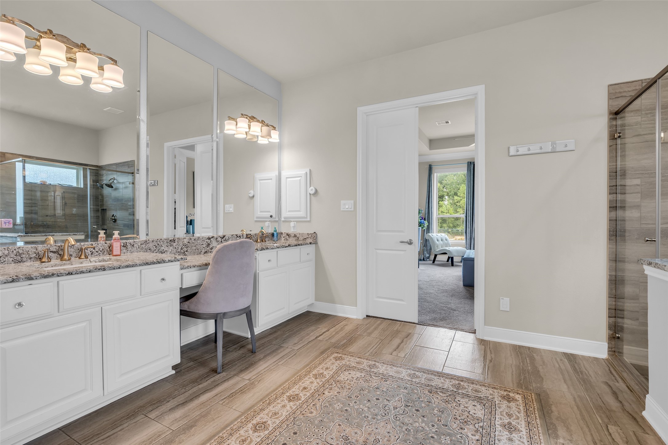 7211 Julie Pond Lane Spring, TX 77389 - Photo 24 of 45 Spacious bathroom featuring dual vanities with granite countertops, elegant lighting, and a large glass-enclosed shower, leading seamlessly into a bright bedroom with serene views.