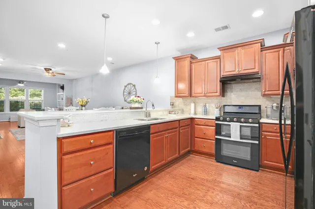 a kitchen with stainless steel appliances granite countertop a stove a sink dishwasher a refrigerator and a oven with wooden floor