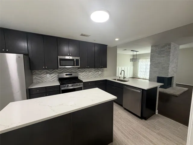a kitchen with granite countertop a refrigerator stove and sink