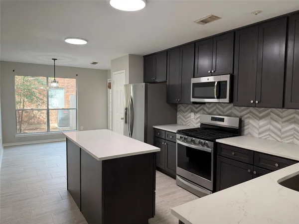 a kitchen with stainless steel appliances kitchen island granite countertop a stove a refrigerator and a sink
