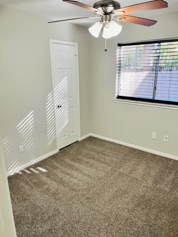 an empty room with windows and fan