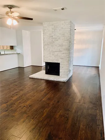 an empty room with wooden floor fireplace and windows