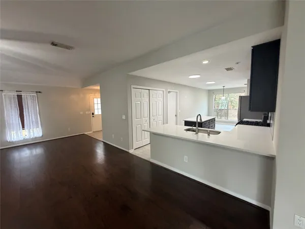 a view of a kitchen with kitchen island a sink wooden floor and a living room view