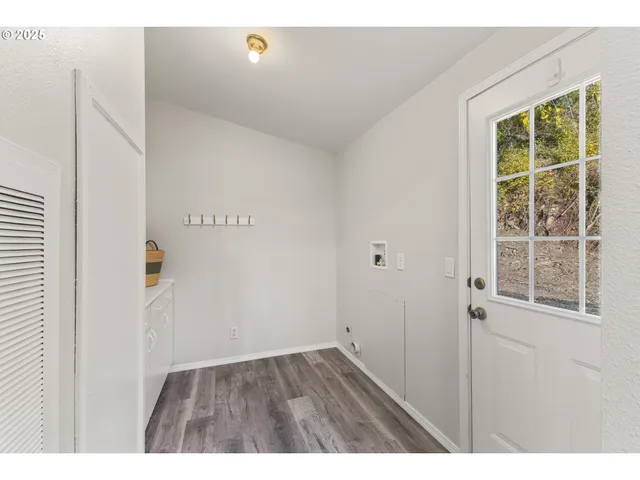 a view of an empty room with wooden floor and windows
