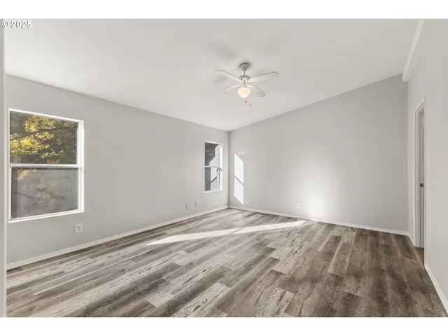 a view of empty room with wooden floor and fan