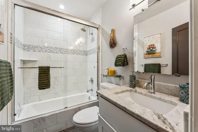 a bathroom with a granite countertop sink a mirror a bathtub and shower