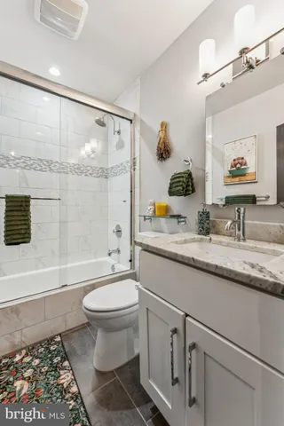 a bathroom with a granite countertop sink mirror vanity and toilet