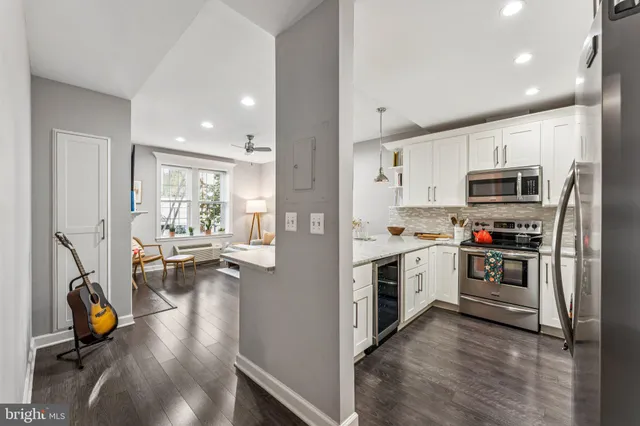 a kitchen with stainless steel appliances a stove top oven a refrigerator a sink and dishwasher with wooden floor