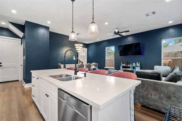 a kitchen with stainless steel appliances kitchen island a large counter top space a sink and a chandelier